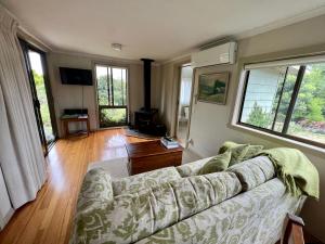 a living room with a couch and some windows at The Little House on The Hill in Badger Creek