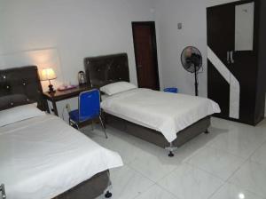 a bedroom with two beds and a desk with a fan at Asmanida Syariah Guest House in Bukittinggi +30 photos