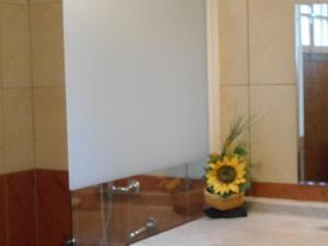 a vase with a sunflower sitting on a counter in a bathroom at L'ESTAGNON in La Plaine des Cafres