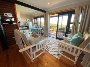 uma sala de estar com cadeiras de baloiço e uma varanda em Tiptol Couple's Retreat em Jeffreys Bay