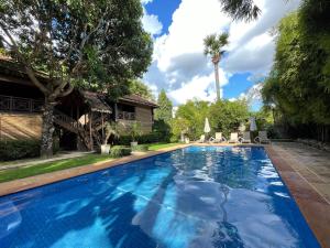 a swimming pool in the backyard of a house with trees at La Palmeraie D'angkor in Siem Reap