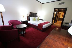 Grand Mayfair Hotel في دبي: غرفه فندقيه بسرير وكرسي