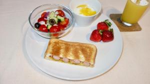 a white plate with a sandwich and a bowl of fruit at Retya in Ishigaki Island