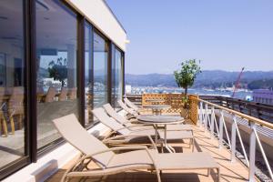 a row of chairs and a table on a balcony at Hotel Ikkeikaku in Kesennuma