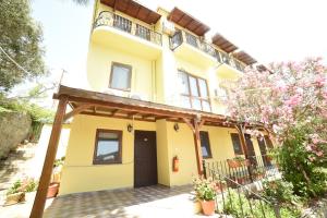 une maison jaune avec une terrasse couverte et une cour dans l'établissement Limonata Hotel Assos, à Assos