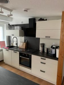 a kitchen with white cabinets and a black counter top at Ferienwohnung Nicole in Bad Harzburg