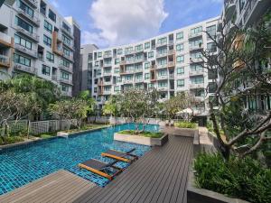a swimming pool with lounge chairs in front of a building at 2BR Service Condo in Sriracha in Si Racha