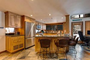 a kitchen with wooden cabinets and a bar with chairs at Fawn Grove Deer Valley Lakeside in Park City