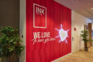 Ink Hotel في دبي: جدار احمر مع لوحة مكتوب عليها نحب ان تكون هنا