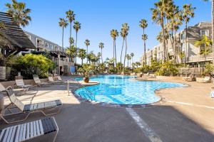 uma piscina com espreguiçadeiras e palmeiras em Modern condo with access to pool & hot tub in great location em Oceanside