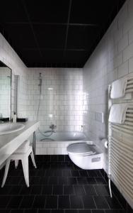 Baño blanco con bañera y lavamanos en Zoom Hotel, en Bruselas