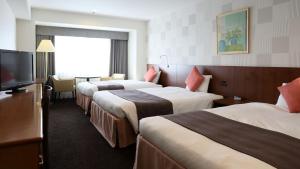 a hotel room with three beds and a flat screen tv at Loisir Hotel Toyohashi in Toyohashi