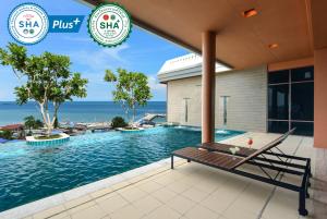 a swimming pool at a resort with the ocean in the background at Hisea Huahin Hotel in Hua Hin
