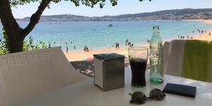 Apartamentos Camping Coroso في ريبيرا: طاولة مع زجاجة واكواب على الشاطئ