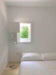 a white bedroom with a bed and a window at Apartamentos Camping Coroso in Ribeira