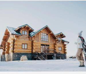 a man standing in front of a log cabin at Lake House Стрижевка in Strizhevka