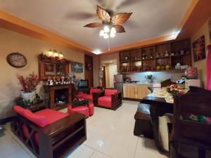 a living room with red chairs and a ceiling fan at Dahilayan Comfy Cabin in Manolo Fortich