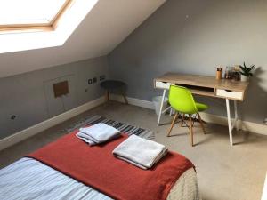 a bedroom with a bed with a desk and a green chair at Twickes Townhouse in London