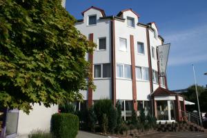 un bâtiment blanc avec un panneau devant lui dans l'établissement Hotel Best one, à Roßdorf