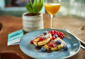 een bord pannenkoeken met bessen en een glas sinaasappelsap bij Beachhouse Hotel in Zandvoort