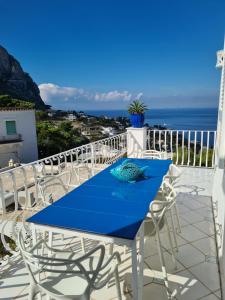 uma mesa azul e cadeiras numa varanda com o oceano em Blu Acquaviva em Capri
