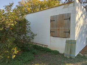 un pequeño edificio blanco con puerta de madera en La Bodega de Villa Bella, en Espartinas