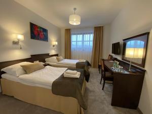 ein Hotelzimmer mit 2 Betten und einem Schreibtisch in der Unterkunft Hotel Tadeusz in Uszew