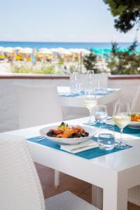 Tirreno Resort في كالا ليبيروتو: طاولة مع طبق من الطعام وكؤوس من النبيذ