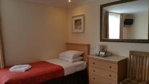 a bedroom with a bed and a mirror and a dresser at Westholme Hotel in Blackpool