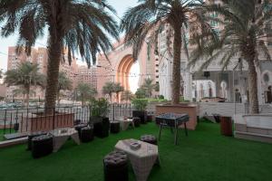 a courtyard with palm trees and a table and chairs at Oaks Ibn Battuta Gate Dubai in Dubai
