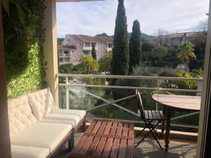 een balkon met een bank en een tafel en uitzicht bij 2P Terrasse vue piscine et jardin tropical La Croix Valmer in La Croix-Valmer