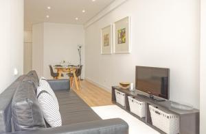 een woonkamer met een bank en een flatscreen-tv bij Luxury Prime Batalha Apartments in Porto