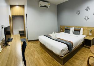 a bedroom with a large bed in a room with a desk at ช้างเผือกเกสต์เฮ้าส์ Changphueak Guesthouse in Nan