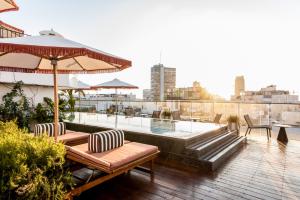 a rooftop patio with a hot tub and chairs and an umbrella at Mayer House in Tel Aviv