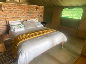 Ce lit se trouve dans une chambre dotée d'un mur en briques. dans l'établissement Limpopo Bushveld Retreat, à Vaalwater