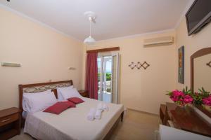 1 dormitorio con 1 cama con sábanas blancas y almohadas rojas en Xenia Apartments, en Vasiliki