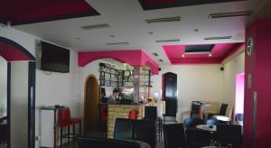a restaurant with pink walls and a person behind a counter at Guesthouse Pink Panther in Udbina