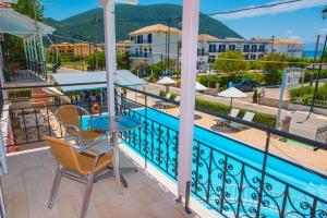 a balcony with a table and chairs and a swimming pool at Xenia Apartments in Vasiliki