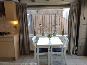 a white table and chairs in a kitchen with a window at TINY HOUSE MIMI Bed by the Sea - Adults only in Zoutelande