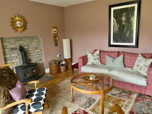 a living room with a red couch and a fireplace at Thistle Cottage, CrannachCottages in Garve