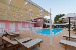 a patio with a pool and chairs and an umbrella at Xenia Apartments in Vasiliki