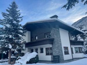 a house with a snow covered tree in front of it at Ferienhaus Plattner in Lienz