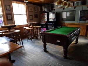 um quarto com uma mesa de bilhar num bar com bancos em The Westgate em Bury Saint Edmunds