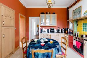 een keuken met een tafel en stoelen en oranje muren bij Villa La Côte du Chat 3* en Bretagne romantique in Hédé