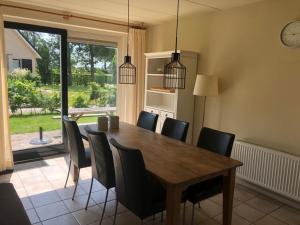 uma sala de jantar com uma mesa de madeira e cadeiras pretas em Vakantiehuis Kiki em Sondel