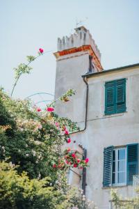 un edificio con persianas verdes y un árbol con flores rosas en Ca di Ni en Finale Ligure