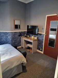 a hotel room with a bed and a desk and a television at Thornhill Blackpool in Blackpool