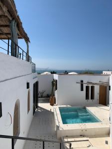 a white house with a swimming pool on a balcony at Dar Gecko in Sidi Kaouki