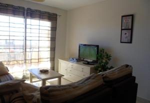 un soggiorno con divano, TV e tavolo di Luxury Apartment Holiday Rental Ne a Nerja