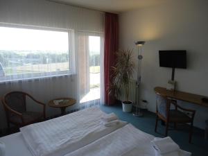 um quarto de hotel com uma cama, uma escrivaninha e uma janela em GreenLine Hotel Hellfeld em Neubrandenburg mais 30 fotografias